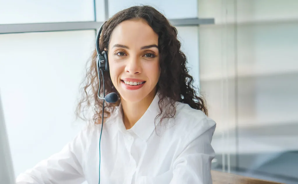 Una consejera trabaja en su escritorio con unos auriculares puestos.