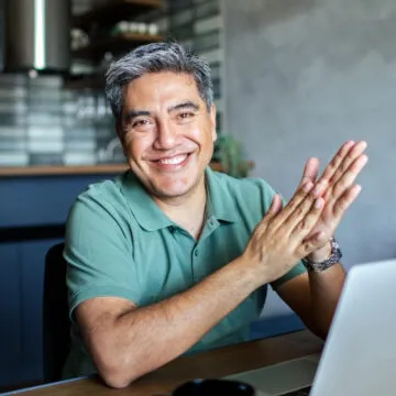 man in green shirt sitting by computer looking straight at camera