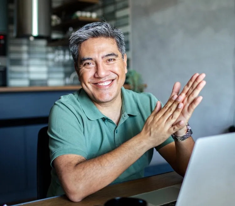 man in green shirt sitting by computer looking straight at camera